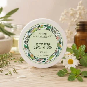 קרם טבעי לטיפול בכפות ההידיים והזרועות בקופסא לבנה פלסטיק, סגורה עם מכסה עם תווית המוצר ועלי צמחים ברקע.